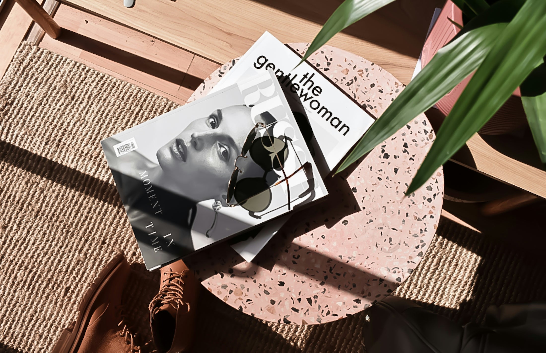 Stack of books on a textured surface with a plant leaf in the foreground