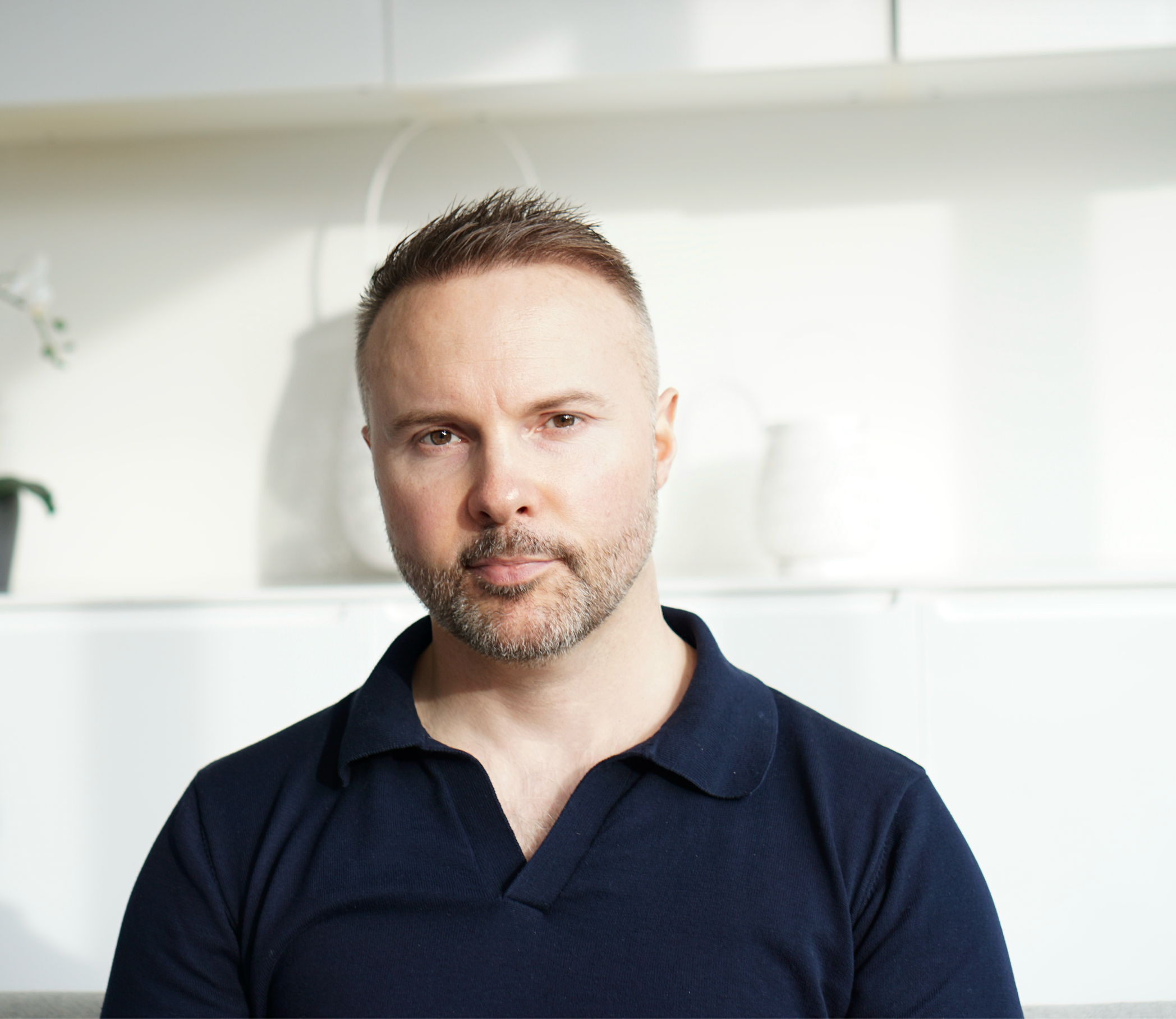 Man wearing a navy blue polo shirt against a white background
